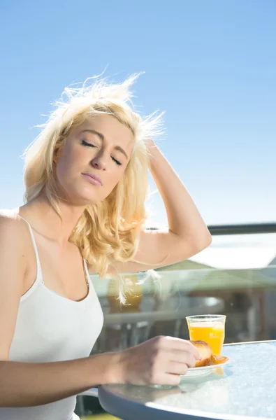 Kvinna njuter av solskenet vid frukost — Stockfoto