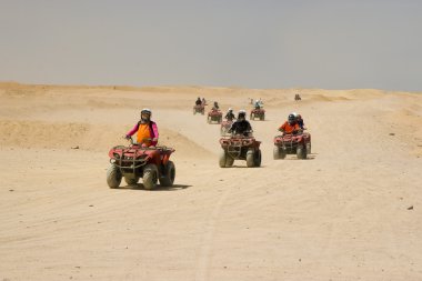 Race on quad in desert clipart