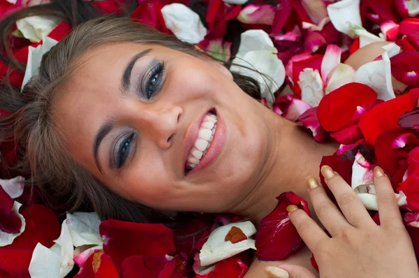 微笑女孩在玫瑰的花瓣 — 图库照片
