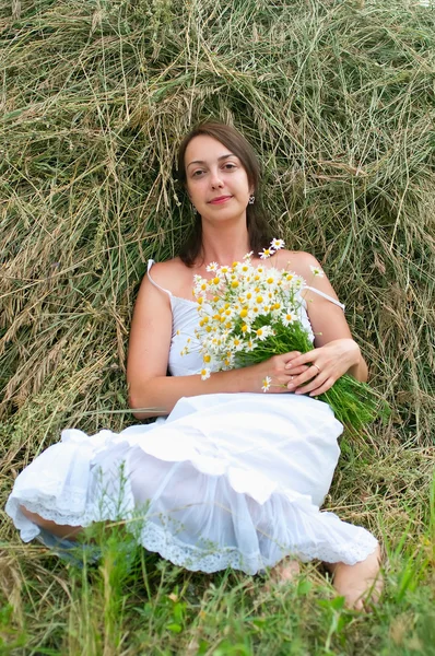 Girl with chamomiles on haystack — Stock Photo, Image