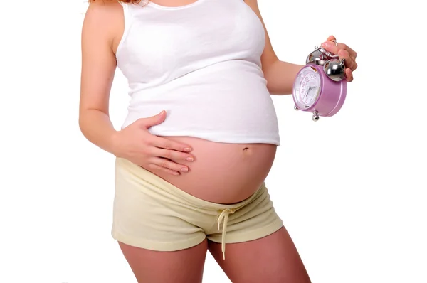 Young redhead pregnant mother holding a clock — Stock Photo, Image