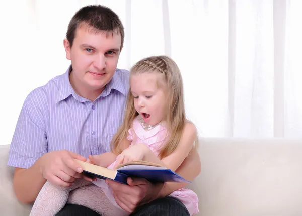 Маленькая девочка сидит на коленях у своего отца — стоковое фото