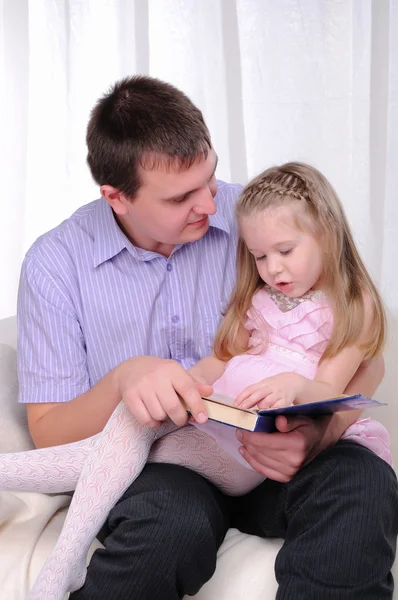Маленькая девочка сидит на коленях у своего отца — стоковое фото