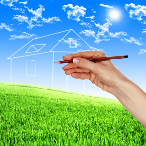 Mão com lápis a arranhar uma casa verde — Fotografia de Stock