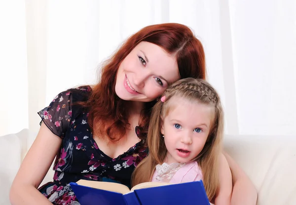 Klein meisje en haar moeder lezen een boek Stockfoto