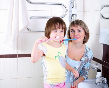 Mother and daughter brushing their teeth clipart