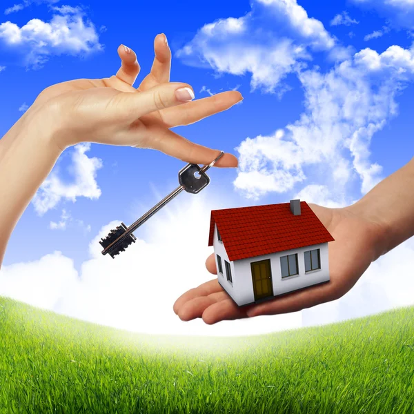 Huis in de handen tegen de blauwe hemel — Stockfoto