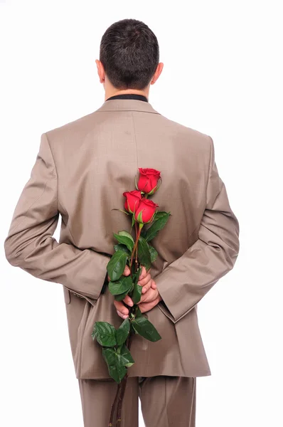 Mladý muž se skrývá za růže — Stock fotografie