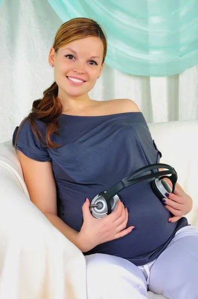 Gravid kvinna anläggning hörlurar — Stockfoto