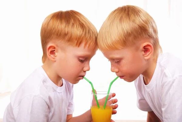 Dvě červené bratr spolu pití šťávy — Stock fotografie