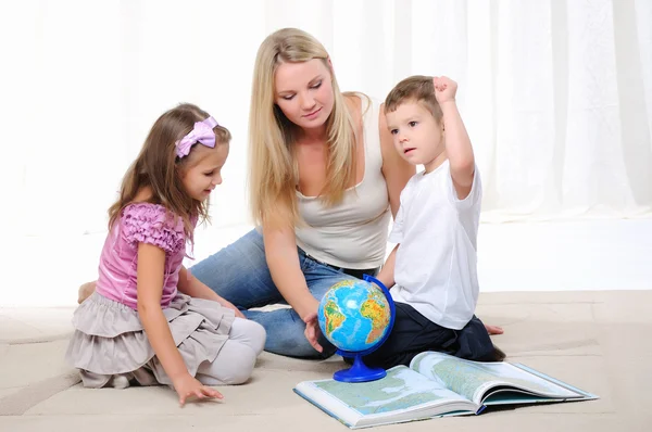 Uma Jovem Mãe Sua Filha Seu Filho Estudando Geografia Atlas — Fotografia de Stock