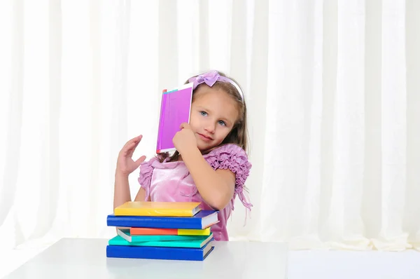 这个小女孩研究文学 坐在白色的桌子上看书 — 图库照片