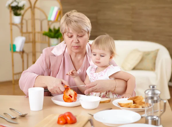 Großmutter füttert Enkelin zu Hause — Stockfoto
