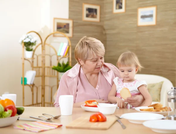 Grandmother feeding granddaughter at home — Stock Photo, Image