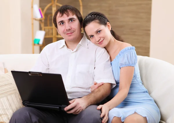 在家里的沙发上坐在便携式计算机上工作的年轻夫妇 — 图库照片