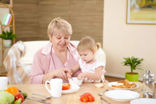 Grandmother Feeding Her Little Baby Granddaughter Home — Stock Photo, Image