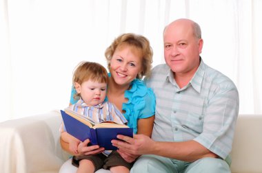 Büyükanne, büyükbaba ve birlikte kitap okuma torunu. ailesinin.