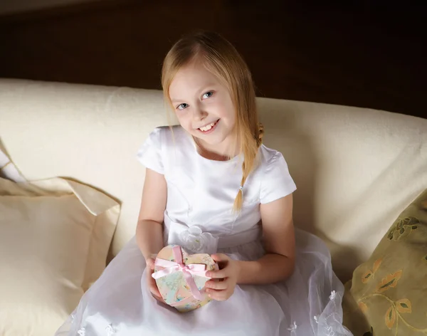 Uma Linda Menina Vestido Branco Sentada Sofá Com Presente Casa — Fotografia de Stock