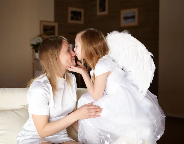 Fille habillée comme un ange embrassant sa mère — Photo