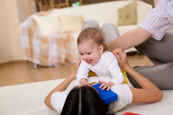 Ung familj hemma spelar med en baby — Stockfoto