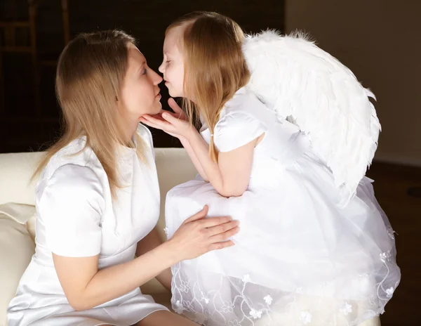 Girl dressed as an angel kissing her mother — Stock Photo, Image