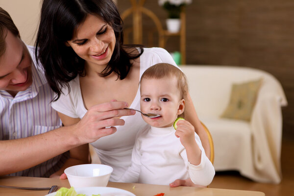 Young family at home having meal together with a baby