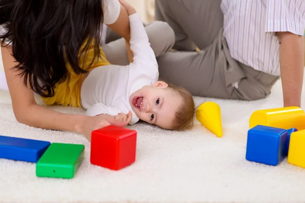 Ung familj hemma spelar med en baby — Stockfoto
