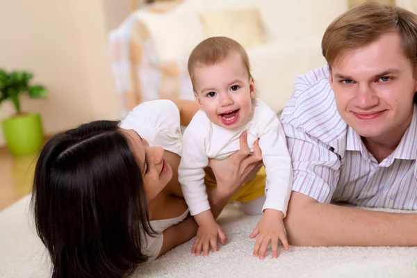 Νεαρή οικογένεια στο σπίτι, παίζει με ένα μωρό — Φωτογραφία Αρχείου