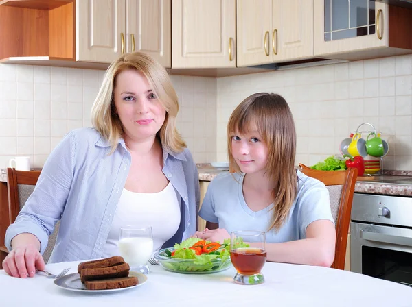 妈妈和年轻的女儿在厨房里一起吃早餐 — 图库照片