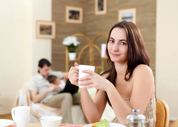 Young mother at home having meal — Stock Photo, Image