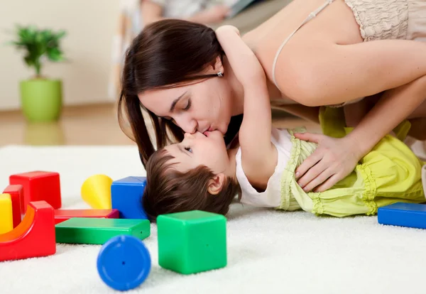 Jovem mãe brincando com seu bebê em casa — Fotografia de Stock