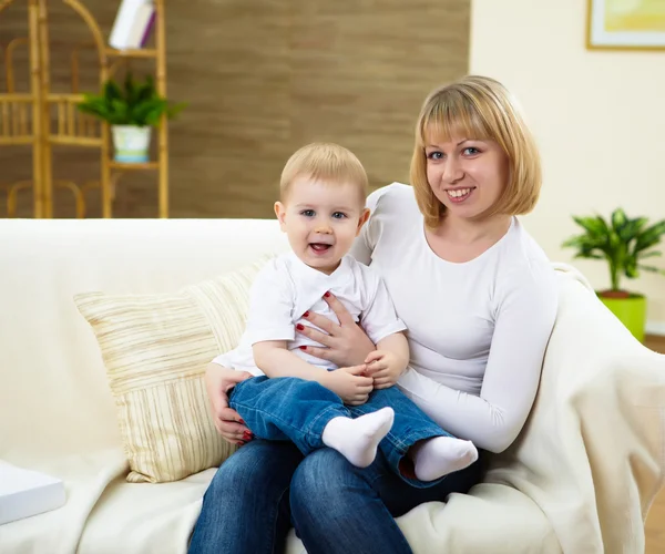 小さな男の子と若い母親一緒に自宅でソファに座って — ストック写真