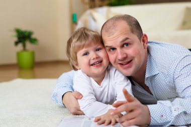 Father and son playing on the floor at home clipart