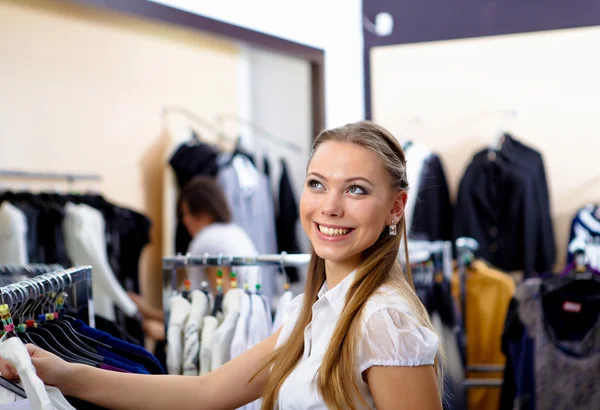 Ung kvinna i en butik köper kläder — Stockfoto