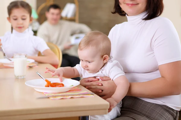 A young mother feeding her baby at home — Stock Photo, Image