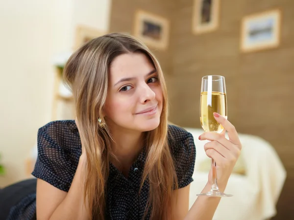 Молода дівчина п'є шампанське вдома — стокове фото