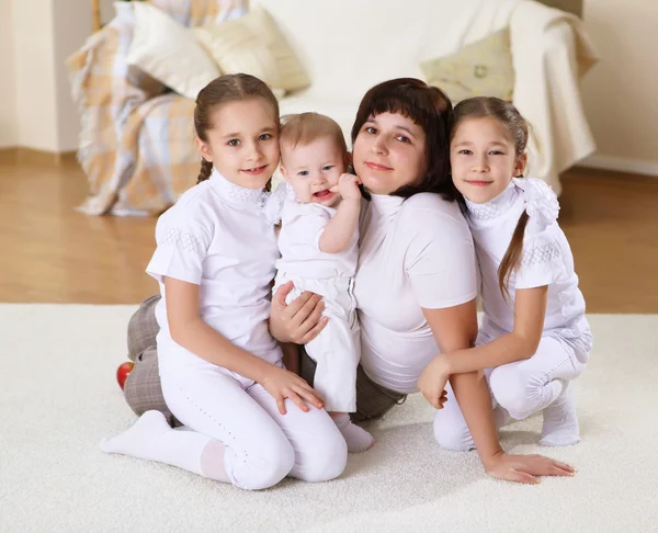 Молодая мать с тремя дочерьми дома — стоковое фото