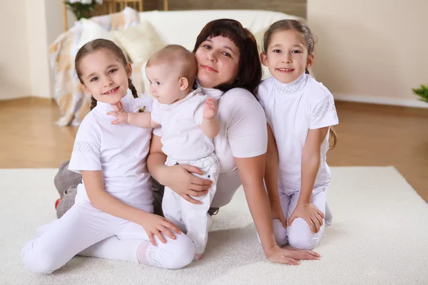 En ung mamma med hennes tre döttrar hemma — Stockfoto