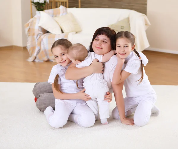Een jonge moeder met haar drie dochters thuis — Stockfoto