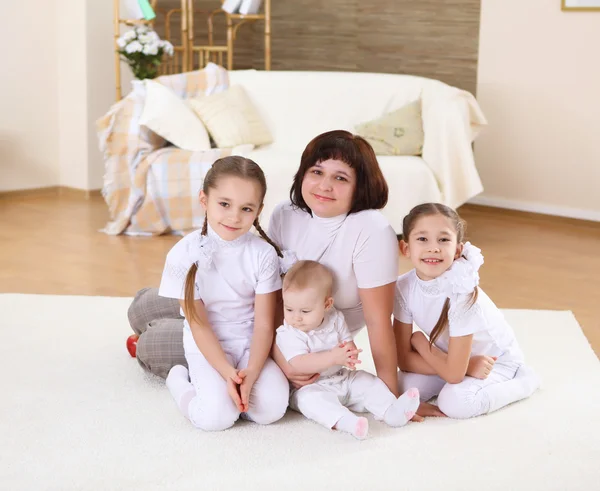 Uma jovem mãe com suas três filhas em casa — Fotografia de Stock