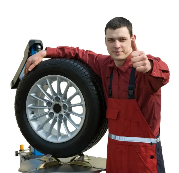 Yakışıklı genç araba tamircisi ile tekerlek — Stok fotoğraf
