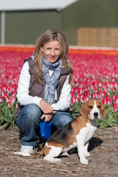 Meisje met haar hond op bloem veld — Stockfoto