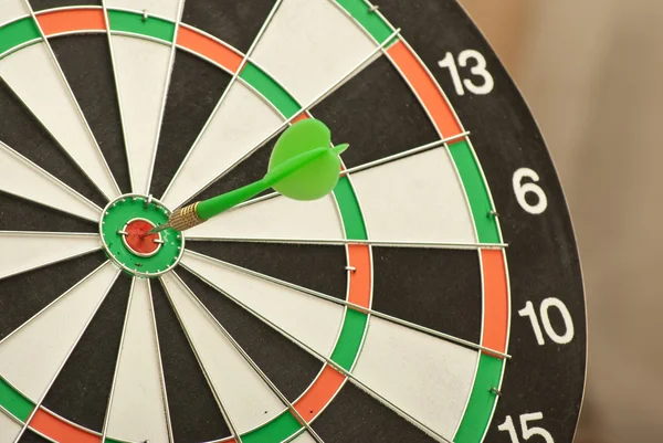 Dart board with green dart — Stock Photo, Image