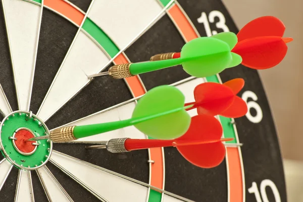 Dart board with red and green darts — Stock Photo, Image