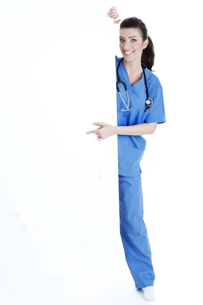 Sorrindo jovem enfermeira apontando placa em branco — Fotografia de Stock