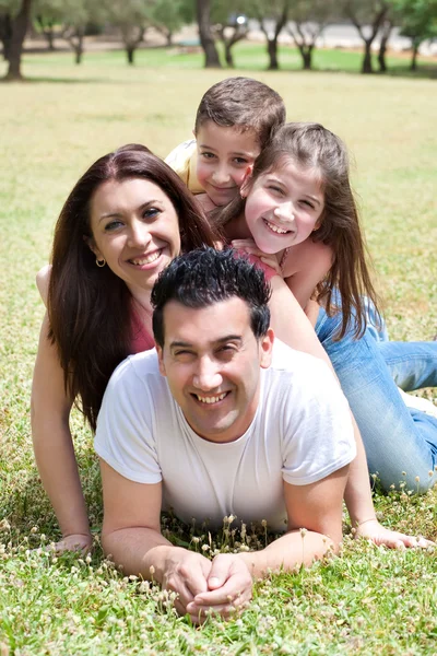 Lycklig familj liggande i gräsplan — Stockfoto