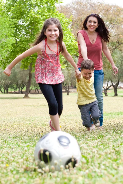 Childrens playing soccer with mother Royalty Free Stock Photos