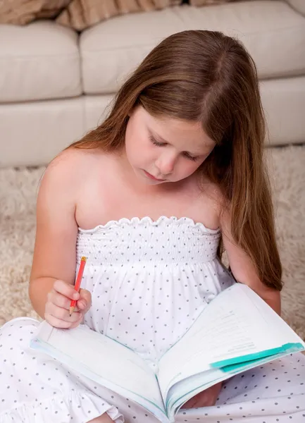 Junges Schulmädchen liest Buch im Wohnzimmer — Stockfoto