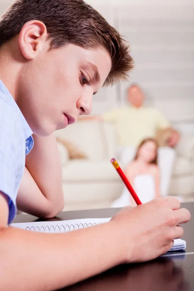Ung tonåring skriver i sin anteckningsbok i vardagsrum — Stockfoto