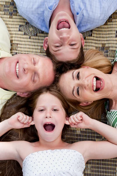 Счастливая семья из четырех человек лежит на ковре с головами вместе — стоковое фото